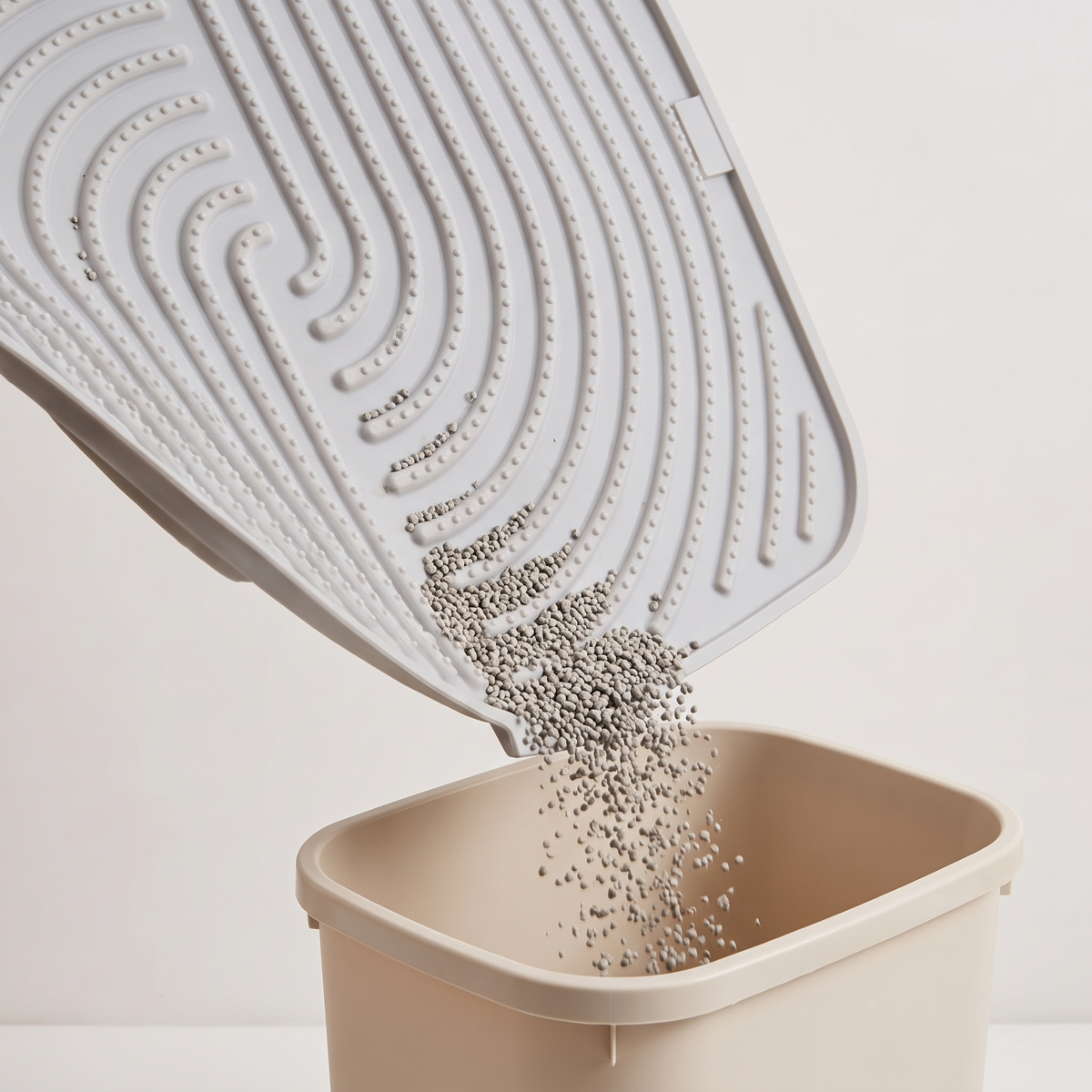 The mat tilted to pour collected litter granules into a bin